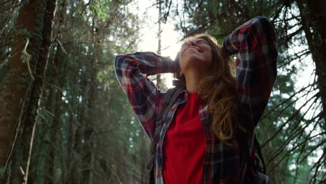 joyful woman taking break during hike in woods. smiling girl standing in forest