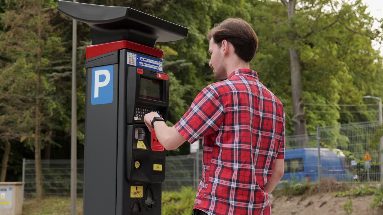 Un giovane usa il parchimetro per pagare il parcheggio dell'auto