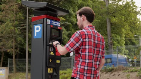 young man use parking meter to pay for car parking