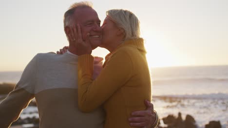 Senior-couple-embracing-each-other-alongside-beach