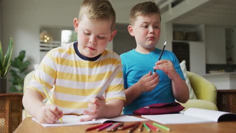 caucasian boy with his brother sitting at table and learning at home