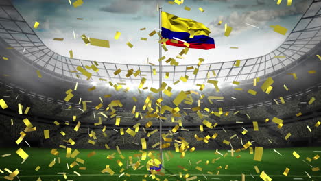 confeti dorado cayendo sobre agitando la bandera de colombia contra el estadio deportivo en el fondo