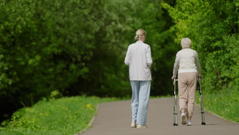 woman assisting elderly person walking in park