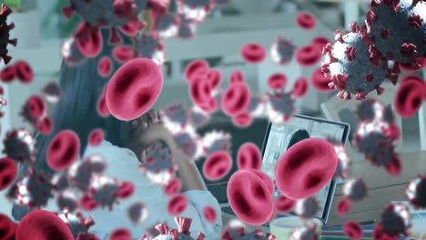 Animation-of-covid-19-cells-and-red-blood-cells-over-businesswoman-using-laptop