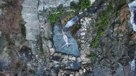 naturally-formed pool, textured rock surface, young woman, aerial reveal