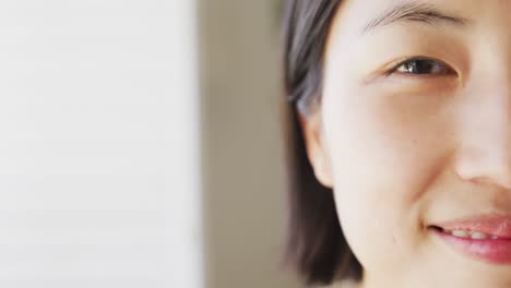 portrait of happy asian woman looking at camera in living room