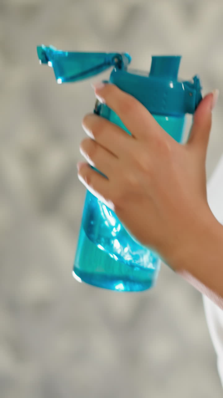 여자 운동 선수가 물병을 들고 훈련을 하고 있는 모습. 여자 선수가 물을 들고 운동 병을 들고 트레드밀을 달리고 있는 모습. 운동 중에 물의 균형이 느리게 움직이는 모습.