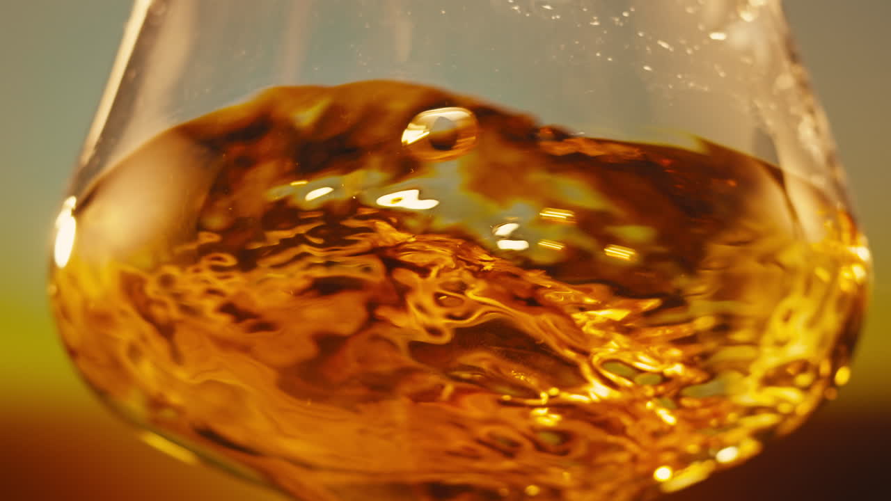 Orange or white wine bottle and glass against a sunset in a peaceful vineyard, pouring of ecological natural wine.