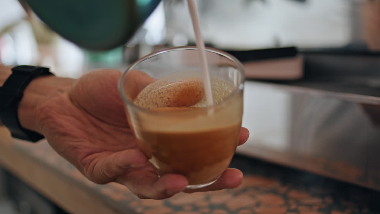 las manos del barista preparando capuchino en la cafetería con la máquina de espresso de cerca.
