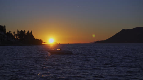 wavy ocean with silhouetted motorboat during golden hour