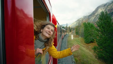 happy female traveller lean out of train window