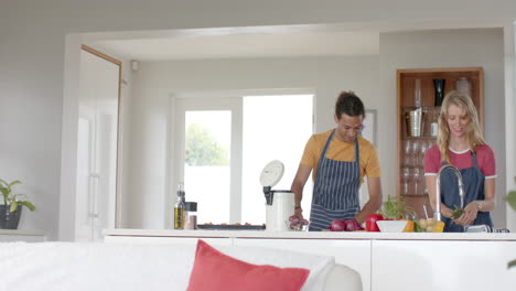 una pareja feliz cocinando y tirando desechos en la cocina, en cámara lenta.