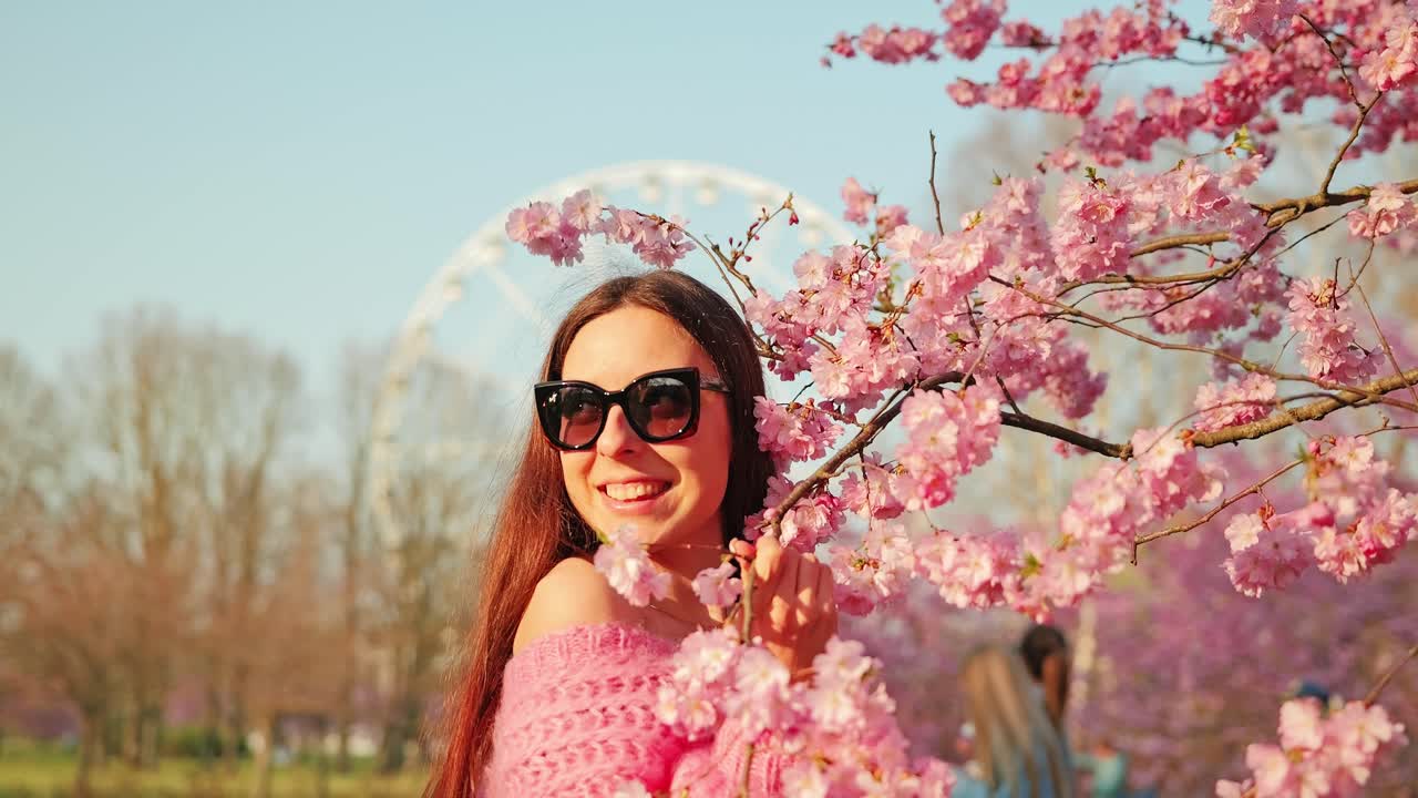 Slow motion smiling woman hugging cherry blossoms at sunset in Riga Victory park