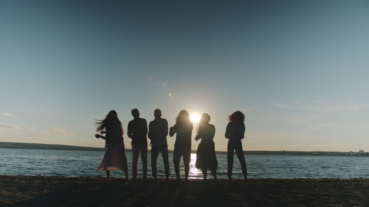 Friends enjoying a sunset at the river beach