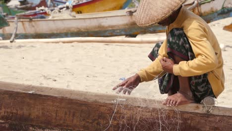 indonesian fisherman untangling a fishing net