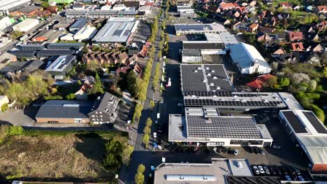 main street in industrial american district at sunset time. cars on tree-lined street. warehouse and company buildings with modern solar panels on roof. aerial top down flyover shot.