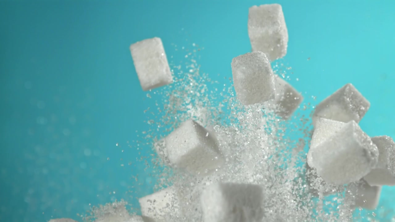 Cámara lenta de terrones de azúcar y azúcar granulada dispersándose