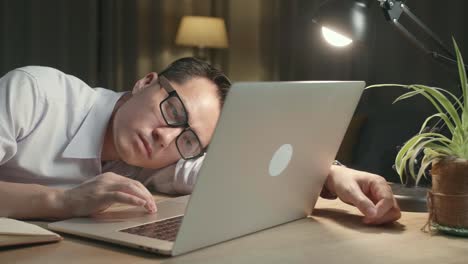 overworked man leaning on laptop