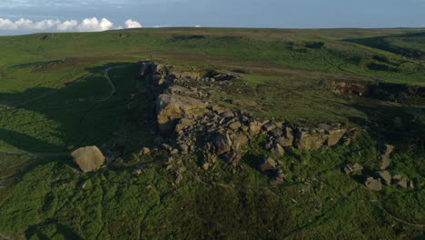 Einrichtung-Einer-Drohnenaufnahme,-Die-über-Die-Felsformation-Kuh-Und-Kalb-Fliegt,-Mit-Menschen,-Die-Zur-Goldenen-Stunde-West-Yorkshire,-Großbritannien,-Auf-Felsen-Auf-Ilkley-Moor-Saßen