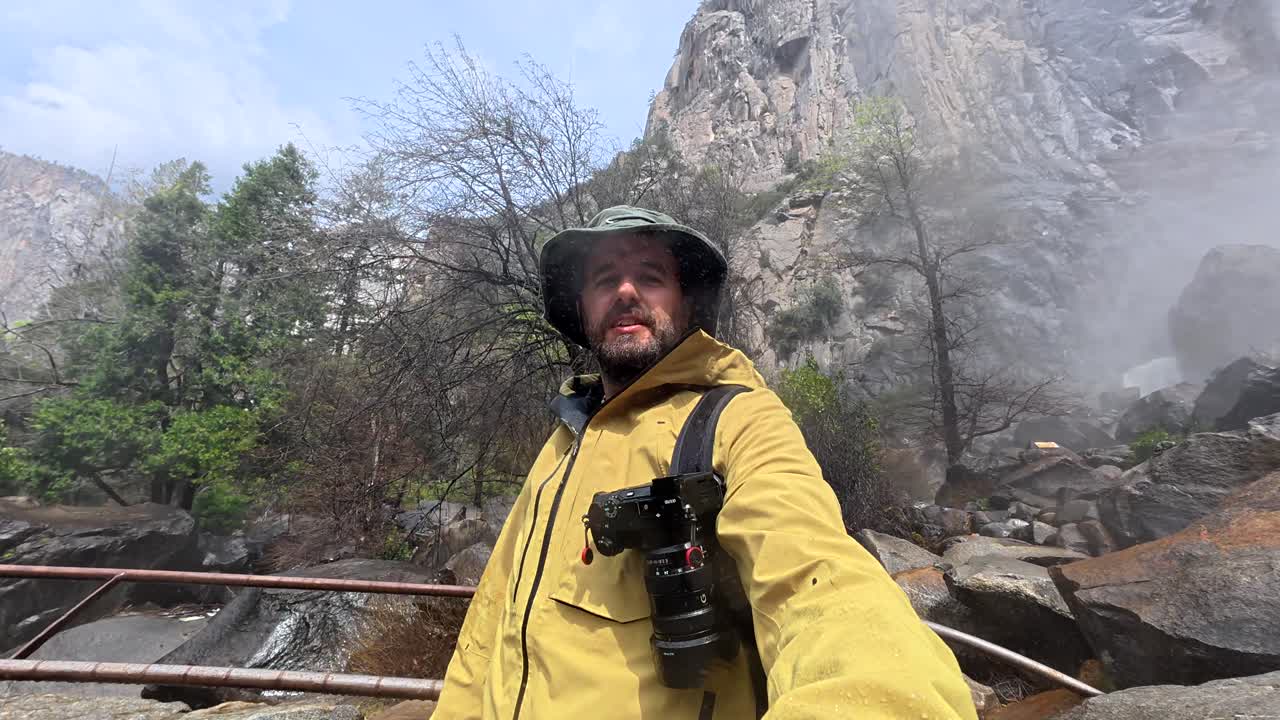 Man Taking Selfie Video in Front of a Powerful Waterfall