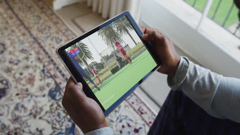 compuesto de un hombre sentado en casa, viendo un partido de hockey en la tableta