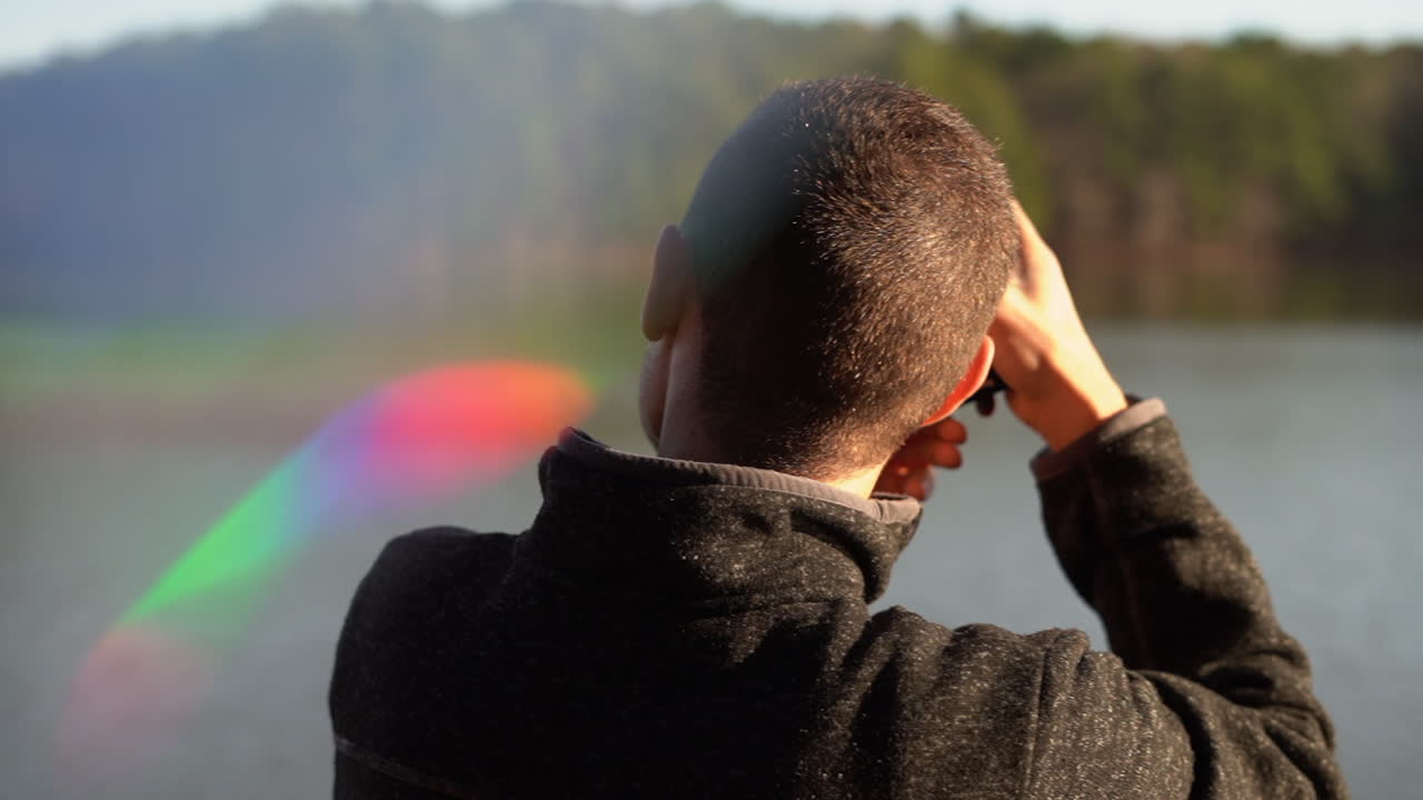 joven fotógrafo con una cámara dslr tomando una foto de paisaje de un lago en un bosque de pinos - fuga de luz y destello de lente