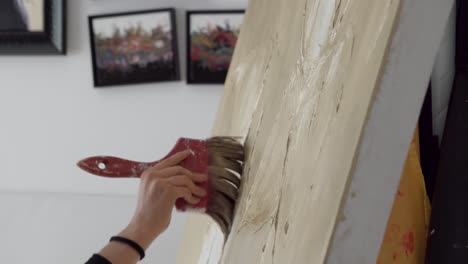 large painting brush holds by a painter working on abstract art canvas