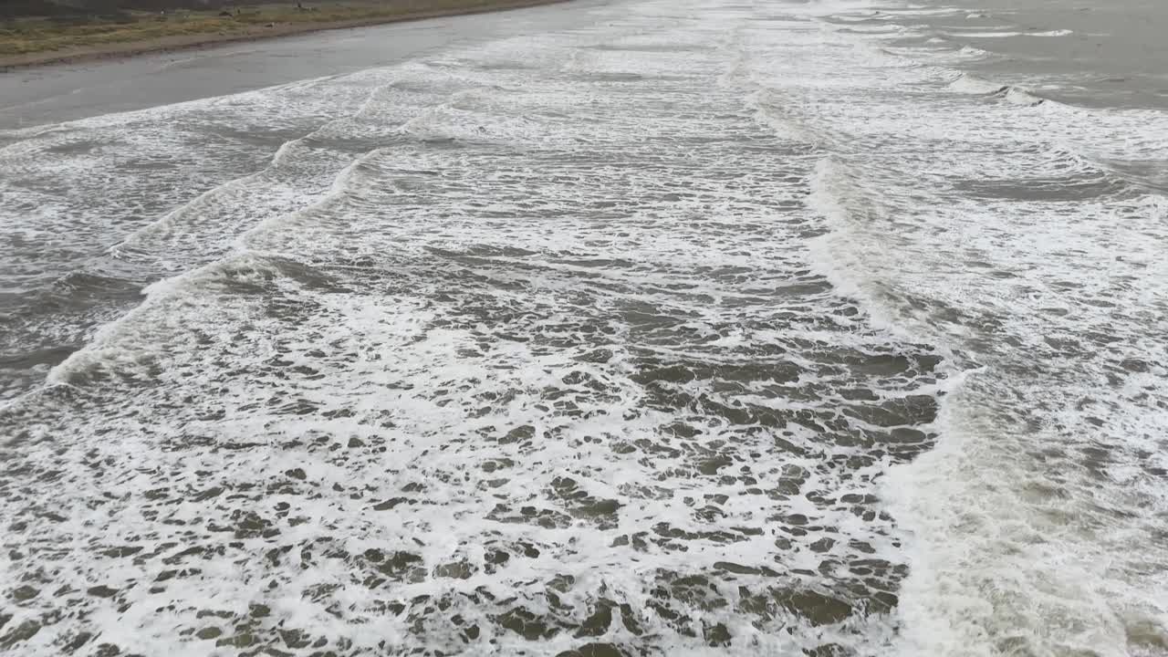 Aerial drone footage of agitated rough ocean waves in winter on east coast of Wales United Kingdom stormy sea dramatic weather conditions wild water movement