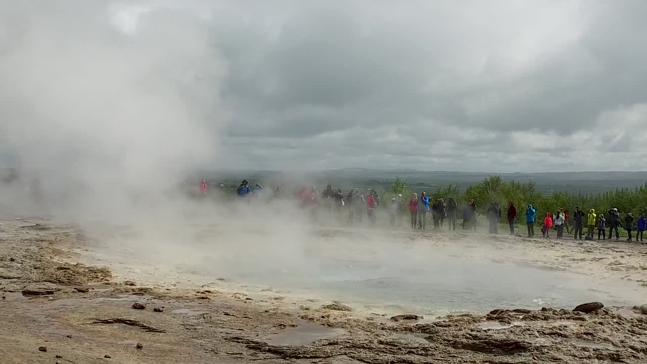 Natural hot springs thermal geyser eruption with tourists on vacation, close up