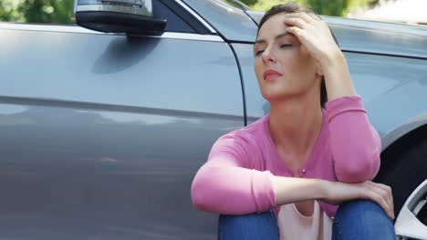 mujer deprimida sentada cerca del coche