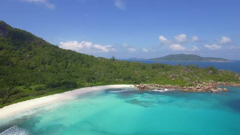 Amplia-Toma-De-Drones-Con-Vistas-A-Una-Playa-Tropical-Vacía-Y-Solitaria-En-El-Paraíso-En-La-Digue,-Seychelles,-Con-Cielo-Azul,-Arena-Blanca-Y-Agua-Turquesa