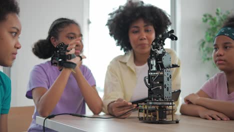 african black kids is playing with robotic arm in a school. group student is controlled by hand. technology and innovation concept.