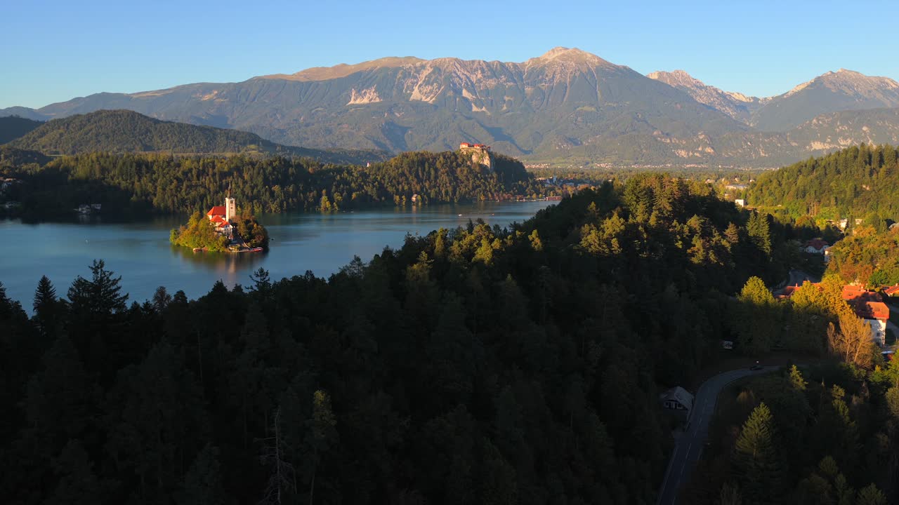 Aerial view of Slovenia's Bled lake, forest, castle, church, majestic mountains