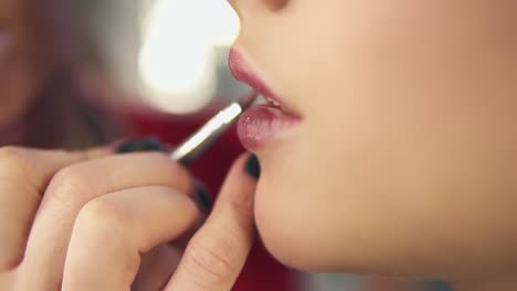 vista de cerca de la mano de un artista de maquillaje profesional usando un pincel especial para aplicar lápiz labial en los labios del modelo trabajando en belleza