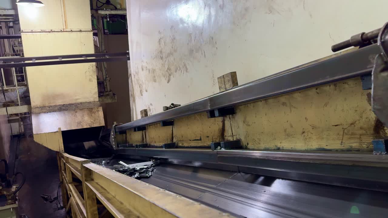 Industrial conveyor belt transporting metal scraps inside a manufacturing factory, showcasing automated production and heavy machinery in operation