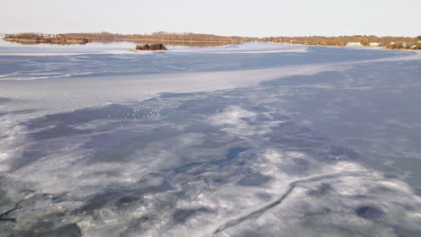 aerial slow forward motion across frozen harbor towards small island, drone