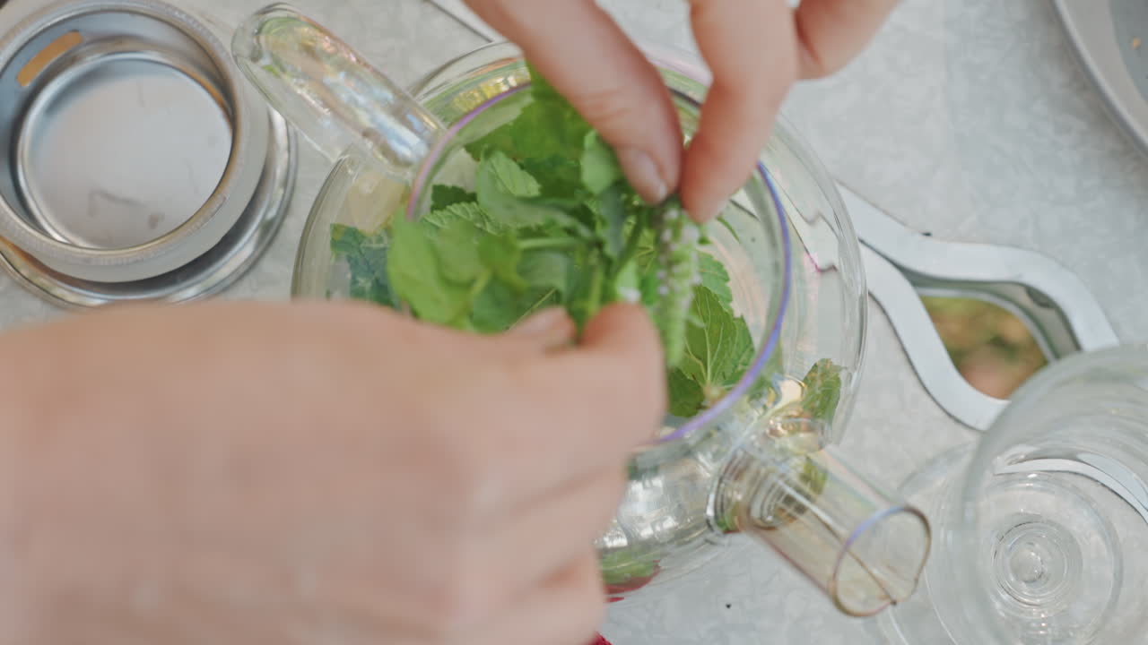 Preparazione meticolosa di un infuso di menta fresca all'aperto, in un'area picnic, come parte di un'attività ricreativa.