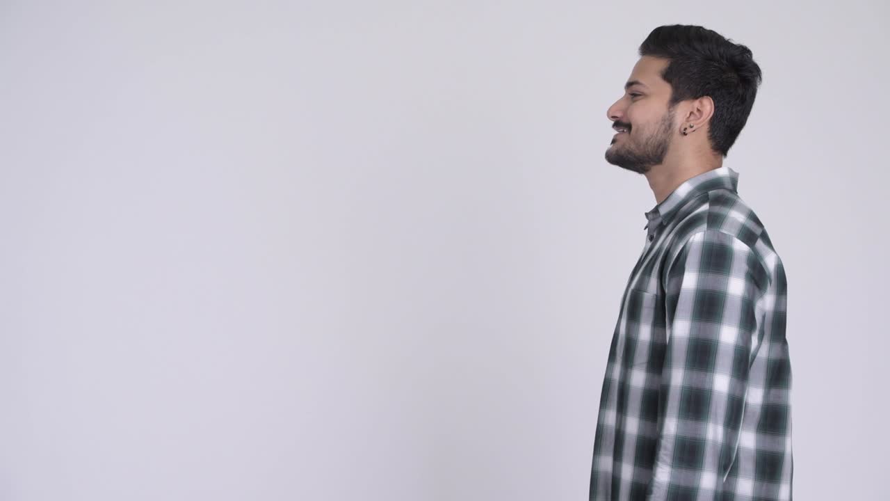 Profile view of happy young bearded Indian hipster man