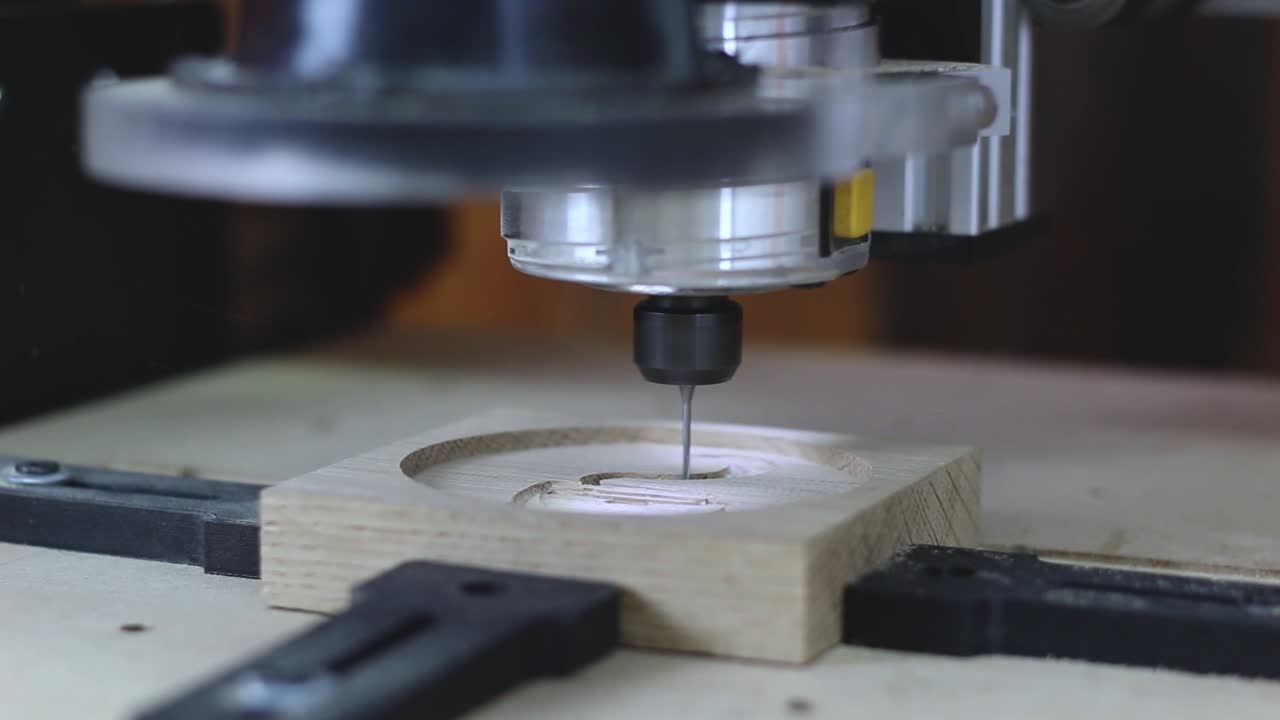A CNC Machine cuts into oak wood. Carving a 3D Model of a coffee cup into the oak wood. High Key lighting and shallow depth of field.