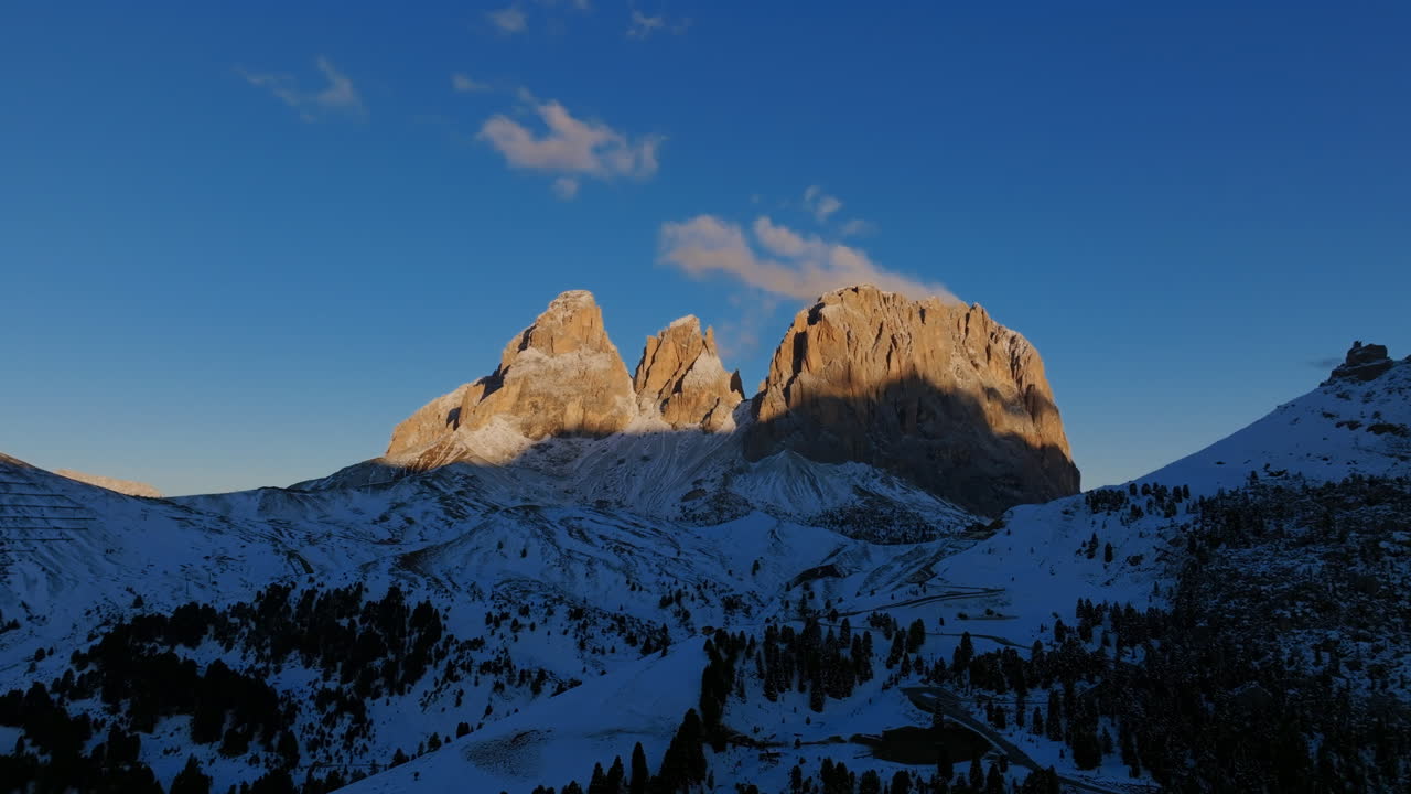 Aerial footage close to the ground moving upwards and flying towards the Colac peaks in the Dolomites in northern Italy during sunrise.