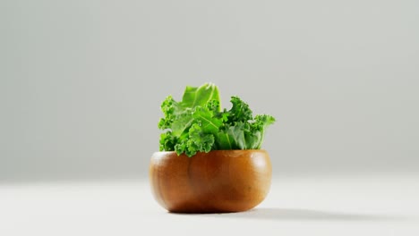 Lettuce-in-wooden-bowl-placed-on-white-surface-4K-4k