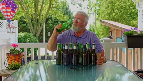 a man relaxes outdoors, seated at a table surrounded by various craft beer bottles. the vibrant greenery and garden decorations create a peaceful atmosphere. he savors the moment in the warm sunlight.