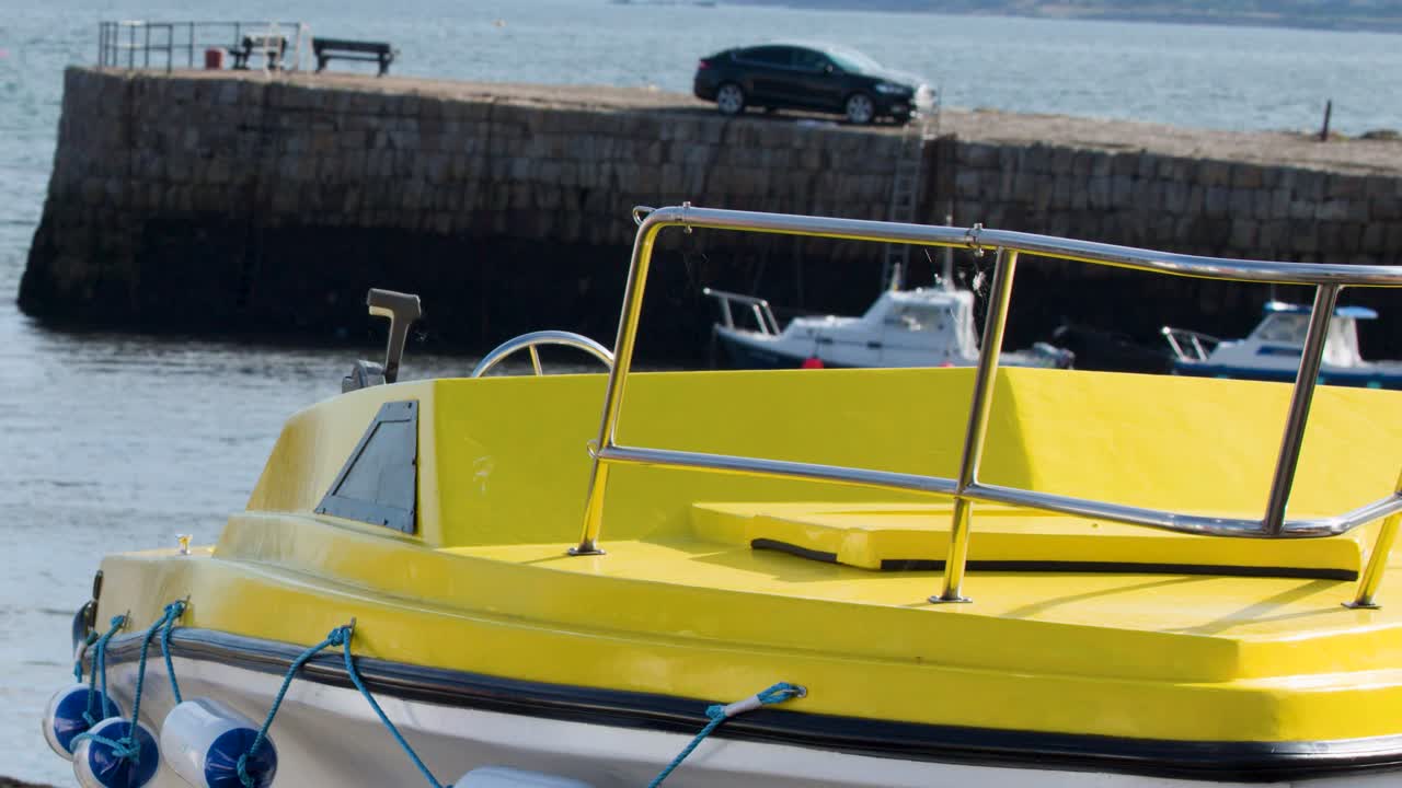 Bright yellow motorboat gently floats in calm harbor, sunlight reflecting, slight camera movement, outdoor setting