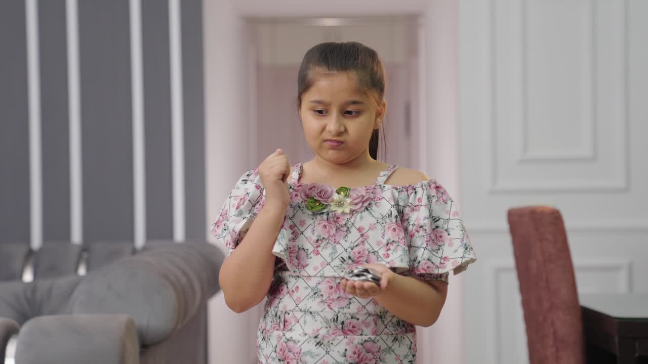 confundida niña india sosteniendo monedas en su mano y pensando