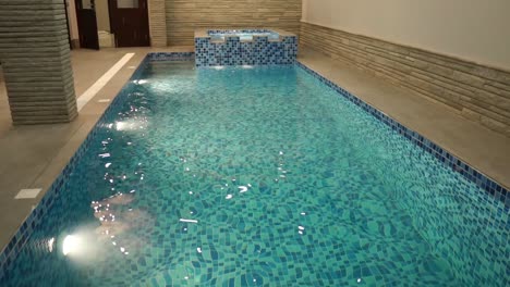 view of indoor swimming pool in luxury home with blue white tiling