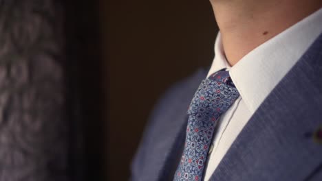 a man puts on a tie and adjusts his collar