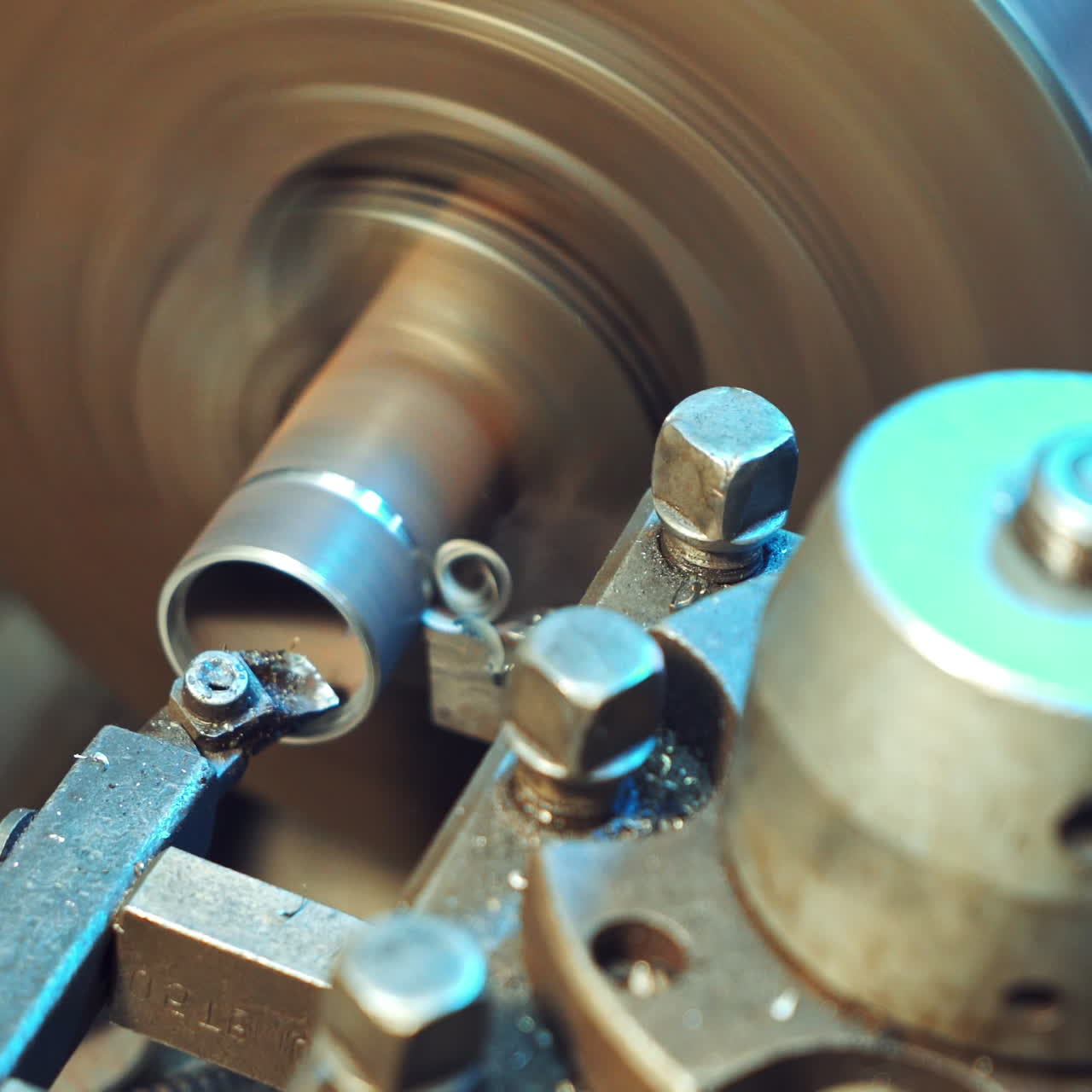 A metal shavings are falling to the floor during processing of part on the lathe in the production. Close-up.