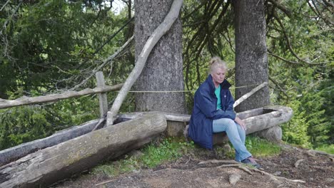 woman sitting on rustic wooden animal water troughs in alpine forest