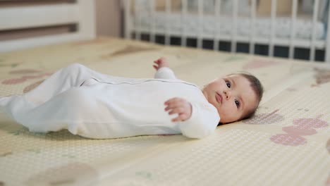 side view of a little baby girl lying on her back on a thermal mat