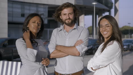 male manager and two female assistants smiling and standing near each other